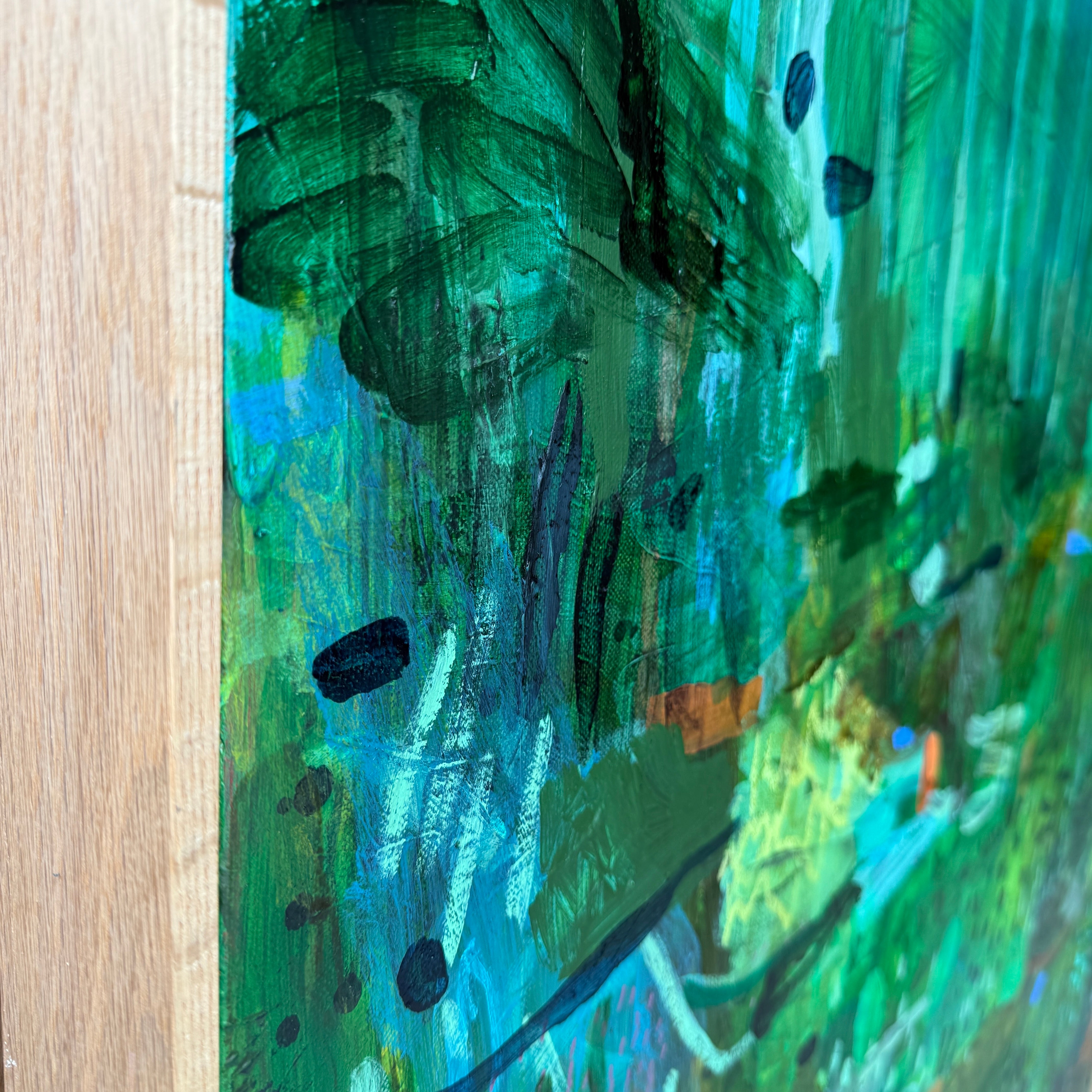 JWG Abstract landscape painting featuring textured brushstrokes of green, teal, and blue with black accents, shown close-up with a light wood Frame at the left edge.