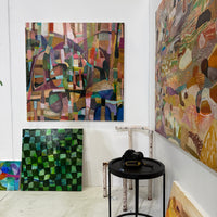Art gallery with various abstract paintings on a white wall.